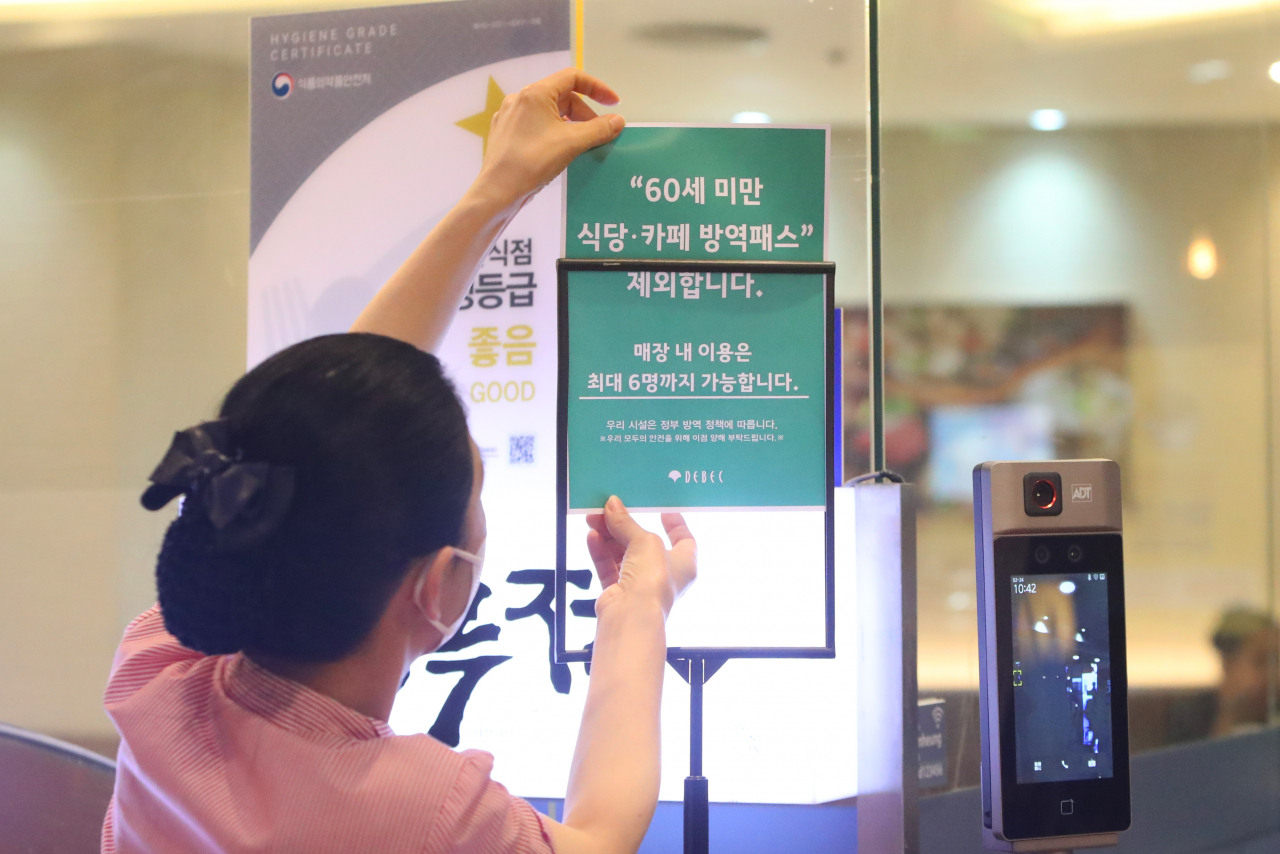 24일 오전 대구 중구 대구백화점 프라자점 내 식당 직원이 방역패스 안내문을 교체하고 있다. 전날 대구지법은 청소년 방역패스에 이어 60세 미만에 대한 식당·카페 방역패스 효력정지 결정을 내렸다. [연합]