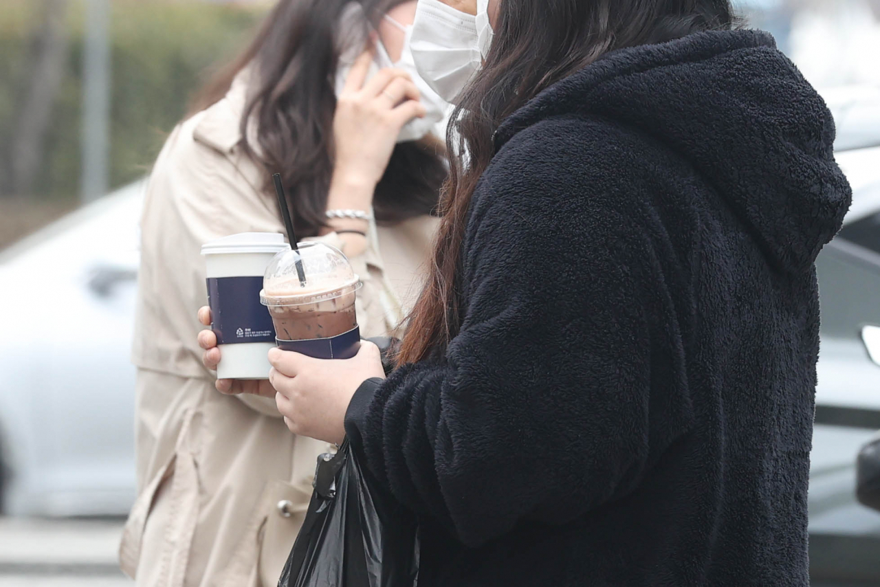 서울 지역 낮 최고기온이 11도까지 올라 큰 일교차를 보인 지난달 28일 서울 종로구 광화문역 인근의 시민들. 각각 따뜻한 음료와 차가운 음료를 들고 있다. [연합]