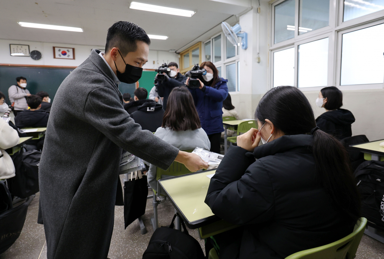 전국 초·중·고교 개학 날인 2일 오전 서울 강남구 도곡중학교에서 선생님이 학생들에게 코로나19 자가검진키트를 나눠주고 있다. [연합]