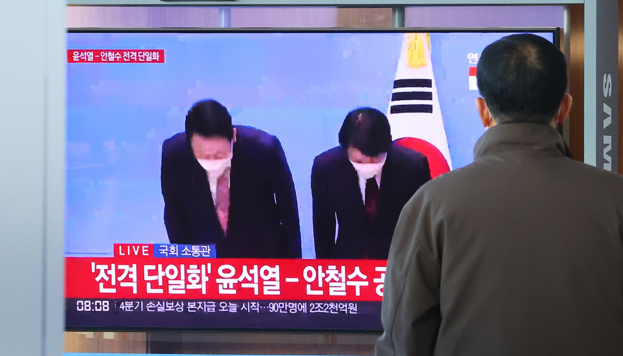 제20대 대선 사전투표를 하루 앞둔 3일 오전 사전투표소가 마련된 서울역 대합실 인근에 설치된 TV화면에 국민의힘 윤석열- 국민의당 안철수 후보 단일화 기자회견이 중계되고 있다. [연합]