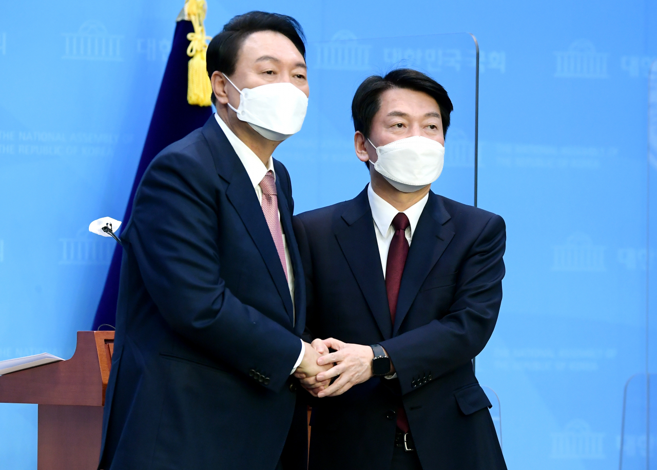 윤석열(왼쪽) 국민의힘 대선후보와 안철수 국민의당 대선후보가 3일 오전 서울 여의도 국회 소통관에서 단일화 기자회견을 마치며 악수하고 있다. [연합]