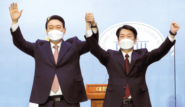 윤석열 국민의힘 대선 후보와 안철수 국민의당 대선 후보가 3일 오전 국회 소통관에서 단일화 기자회견을 마치며 손을 들어 보이고 있다. [국회사진기자단]