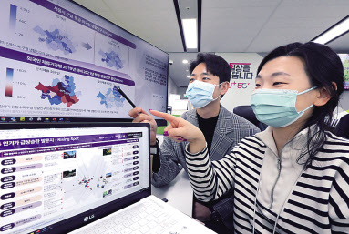 LG유플러스 직원들이 보고서에 수록된 서울시내 인기 방문지 지도를 살펴보고 있는 모습. [LG유플러스 제공]