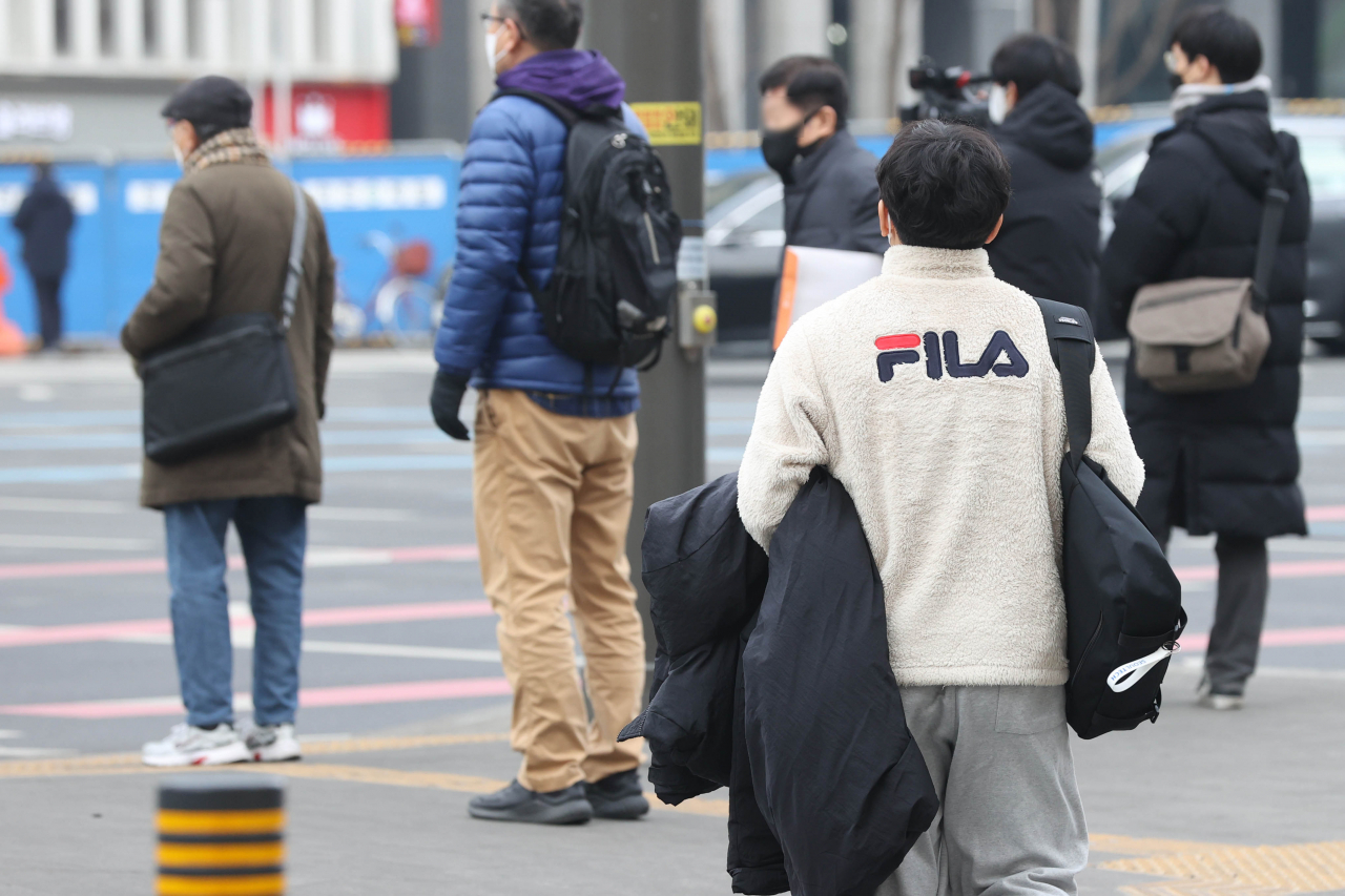지난달 28일 오후 서울 종로구 광화문역 인근에서 한 시민이 기온이 오르자 겉옷을 벗어 들고 있다. [연합]