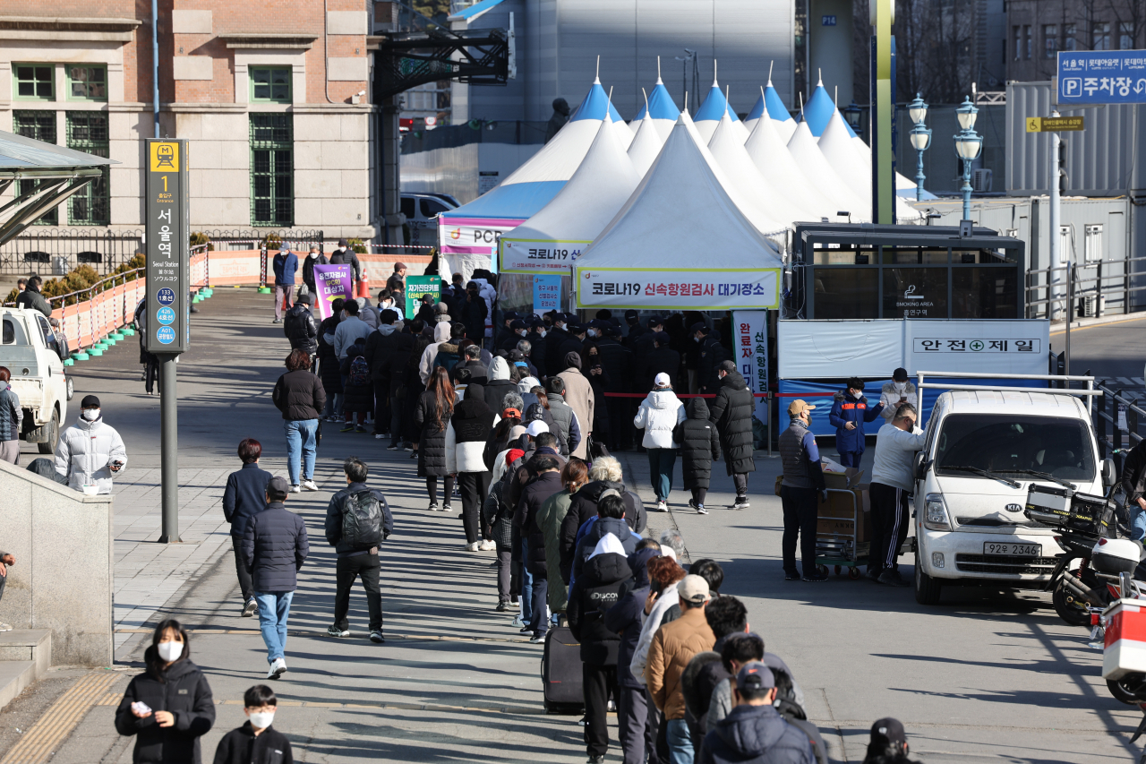 People wait in line to get tested for the coronavirus near a temporary testing center in front of Seoul Station in Seoul on Sunday. (Yonhap)