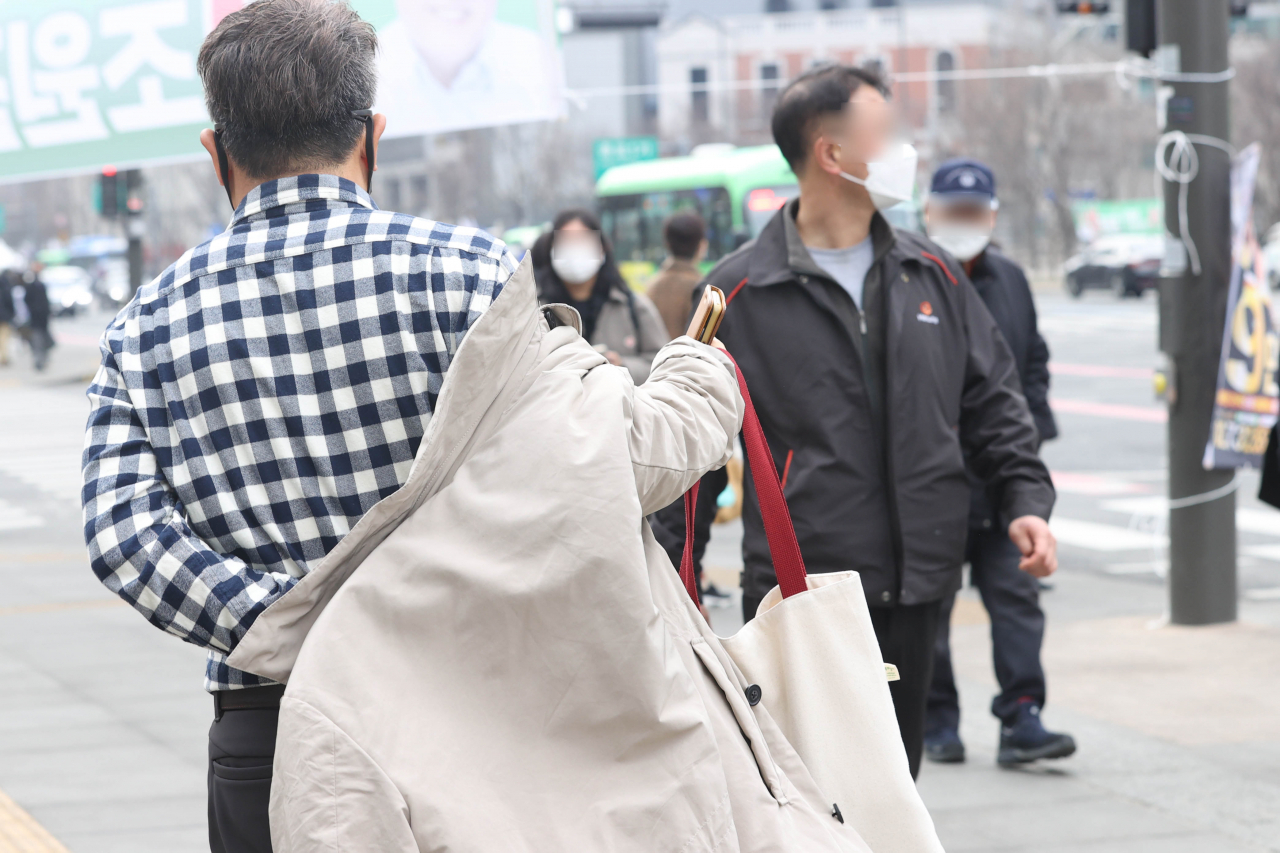 큰 일교차를 보였던 지난달 28일 오후 서울 종로구 광화문역 인근에서 한 시민이 들고 있던 옷을 입고 있다. [연합]