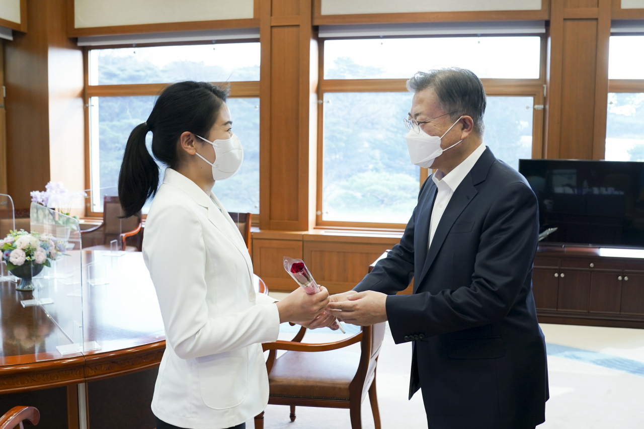 세계여성의 날인 8일 문재인 대통령이 청와대 집무실에서 김현지 간호장교에게 "세계여성의 날을 축하하며 당신을 응원합니다"라는 메시지가 담긴 장미꽃과 함께 격려의 말을 전하고 있다. 연합뉴스