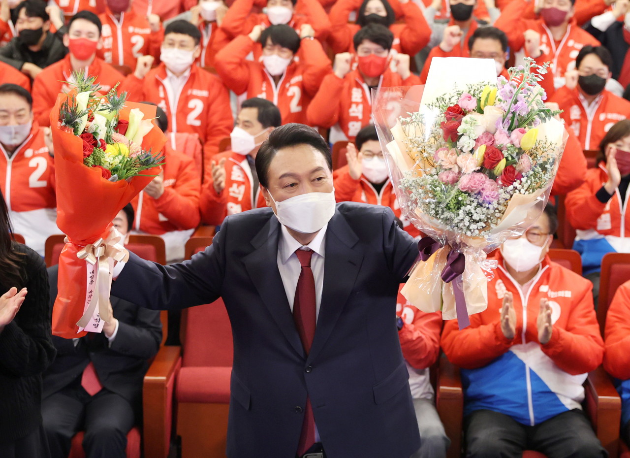 윤석열 제20대 대통령 당선인이 10일 새벽 서울 여의도 국회도서관에 마련된 '국민의힘 제 20대 대통령선거 개표상황실'에서 꽃다발을 들고 포즈를 취하고 있다. [연합]