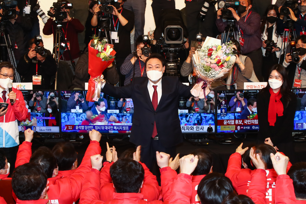 윤석열 제20대 대통령 당선인이 10일 새벽 국회 도서관에 마련된 개표상황실을 찾아 당선 축하 꽃다발을 들어보이고 있다. [국회사진기자단]
