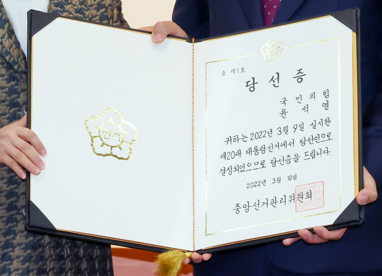 연합뉴스) 안정원 기자 = 노정희 중앙선거관리위원회 위원장이 10일 오전 경기도 과천시 중앙선거관리위원회에서 국민의힘 서일준 의원에게 윤석열 대통령 당선인의 당선증을 전달한 뒤 기념촬영을 하고 있다. [연합]