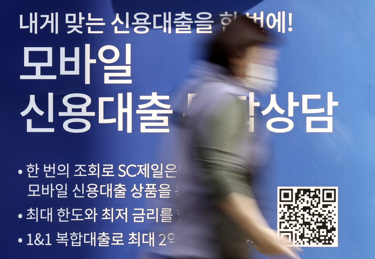 A pedestrian passes by a local bank in Seoul advertising its loan product, in this photo taken on Feb. 11. (Yonhap)