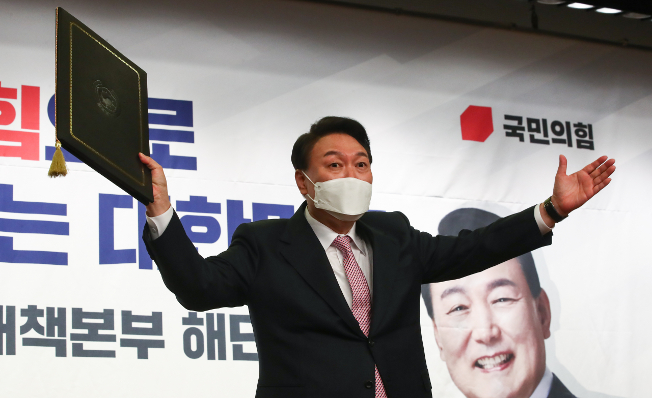 윤석열 대통령 당선인이 10일 오후 서울 여의도 국회 도서관에서 열린 국민의힘 대선 선거대책본부 해단식에서 중앙선거관리위원회로부터 받은 당선증을 들어보이고 있다. [연합]