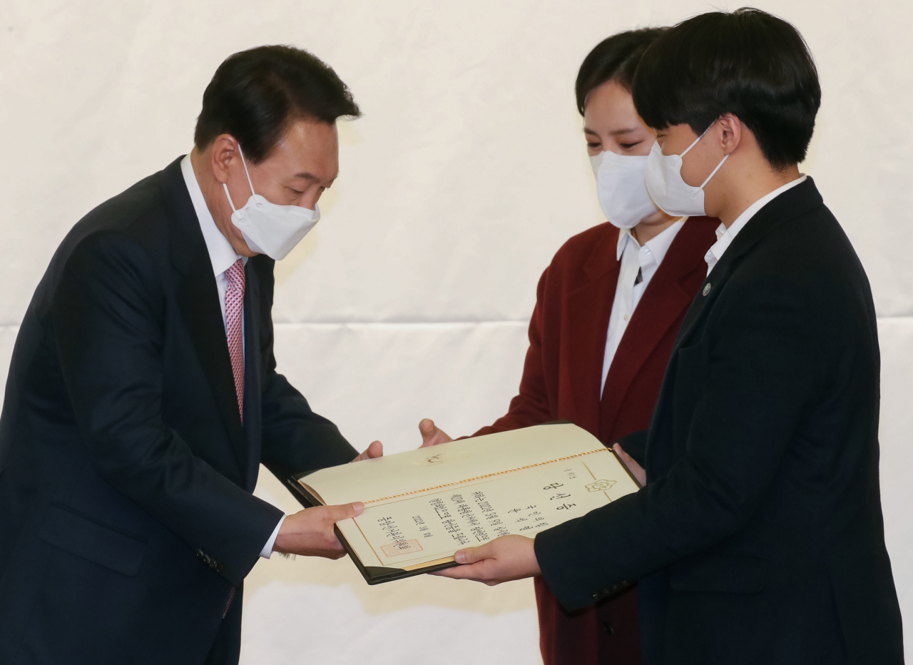 윤석열 대통령 당선인이 지난 10일 오후 서울 여의도 국회 도서관에서 열린 국민의힘 대선 선거대책본부 해단식에서 중앙선거관리위원회로부터 받은 당선증을 청년보좌역에게 전달받고 있다. [연합]