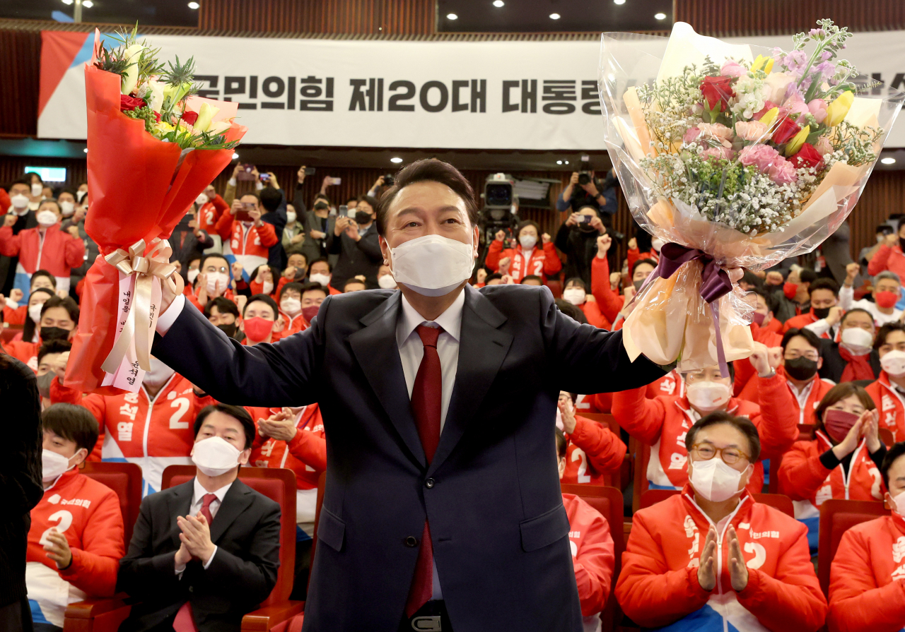 윤석열 대통령 당선인이 지난 10일 새벽 서울 여의도 국회도서관에 마련된 '국민의힘 제 20대 대통령선거 개표상황실'을 찾아 꽃다발을 받은 뒤, 취재진을 향해 포즈를 취하고 있다. [연합]