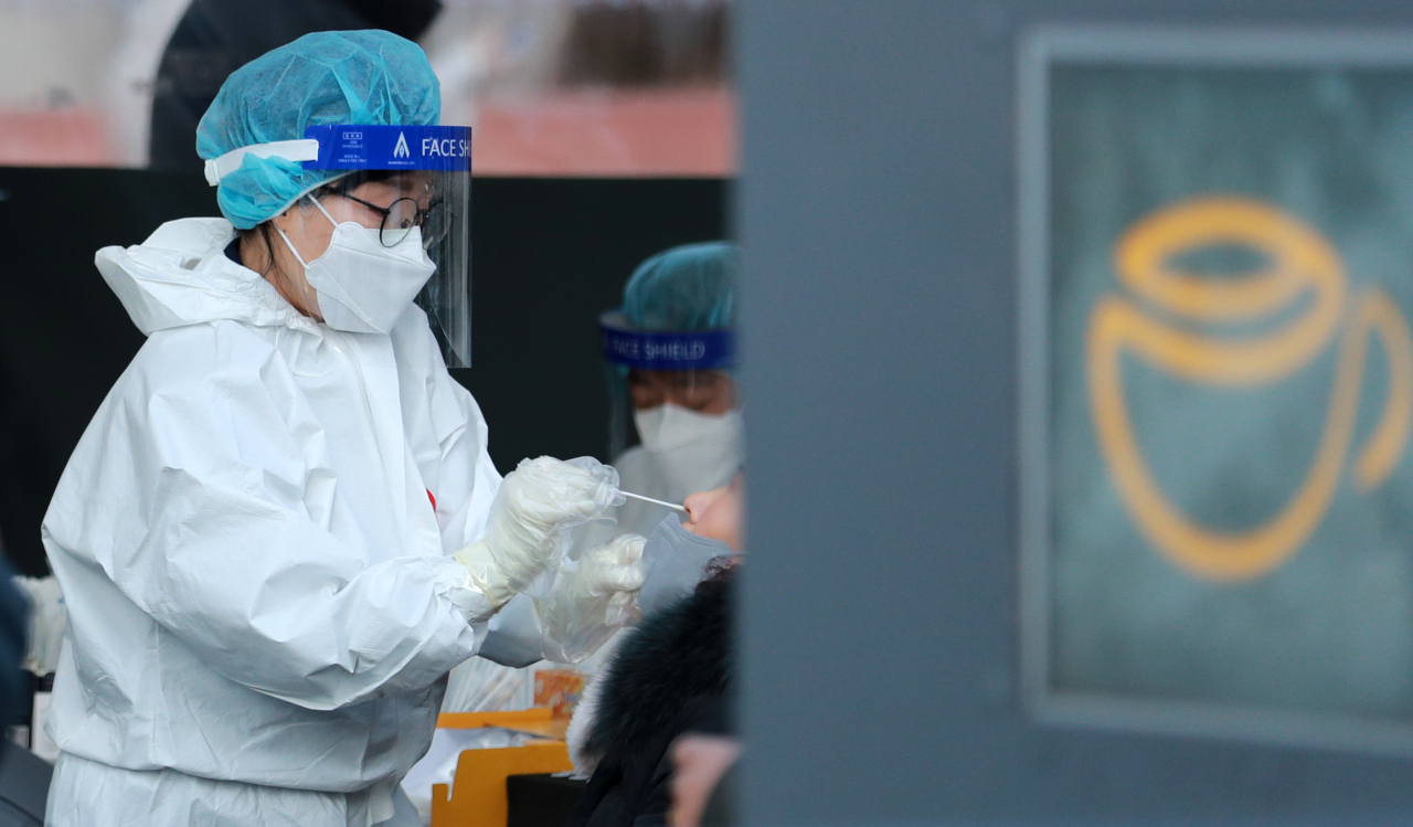 Health care worker takes a nasopharyngeal sample from a person at a testing center outside Seoul Station on Feb. 24. (Yonhap)