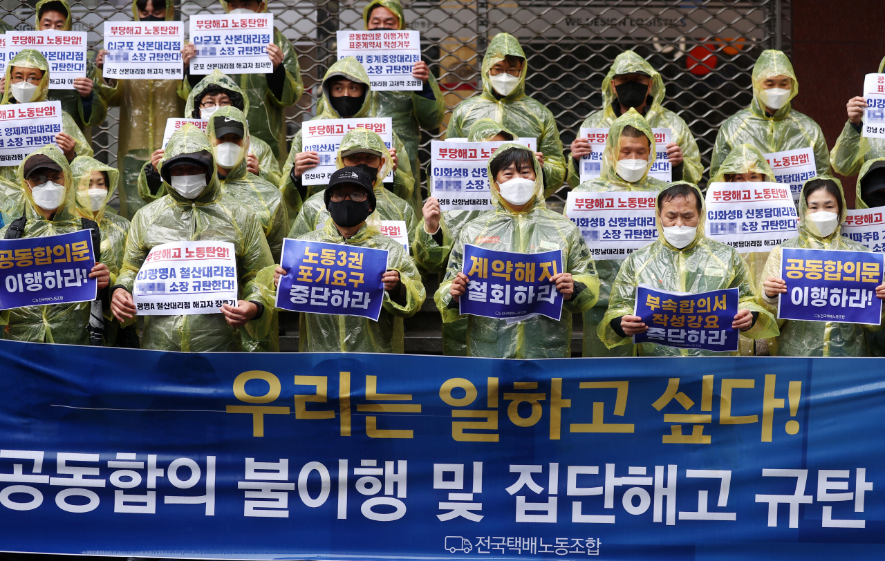 14일 오후 서울 중구 CJ대한통운 본사 앞에서 열린 민주노총 전국택배노조의 ‘공동합의 불이행 및 집단해고 규탄 기자회견’에서 참석자들이 표준계약서 작성 거부와 함께 부당해고 대리점을 규탄하는 손팻말을 들고 있다. [연합]