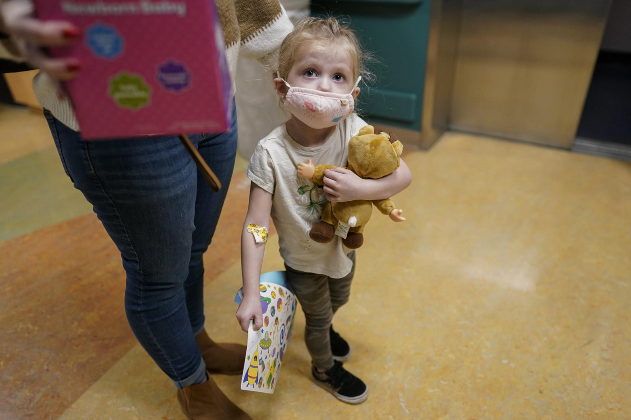 Alyssa Carpenter, 3, waits for the elevator with her mother, Tara Carpenter, with stickers and toys given to her during her followup visit to Children's National Hospital in Washington, Monday, Feb. 28, 2022. (AP Photo/Carolyn Kaster)