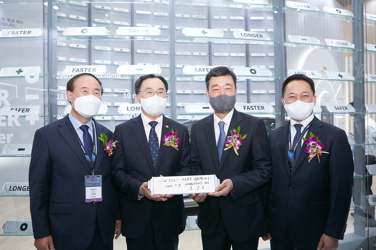 17일 서울 코엑스에서 개막한 ‘인터배터리 2022’에서 문승욱 산업통상자원부 장관(좌측 두번째)이 SK온 부스를 방문해 SK온 배터리 셀에 방명록을 작성한 뒤 지동섭 SK온 사장(우측에서 두번째)과 포즈를 취하고 있다. 사진 좌측은 전영현 한국전지산업협회 회장 겸 삼성SDI 부회장, 우측은 최윤호 삼성SDI 사장. [SK온 제공]