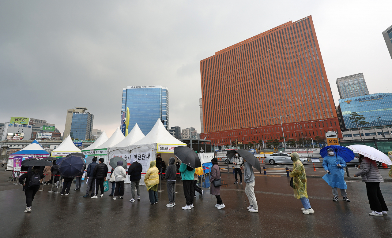 People wait in a long line to receive coronavirus tests at a makeshift COVID-19 testing facility in Seoul on Sunday. The country reported 334,708 new infections on the day. (Yonhap)