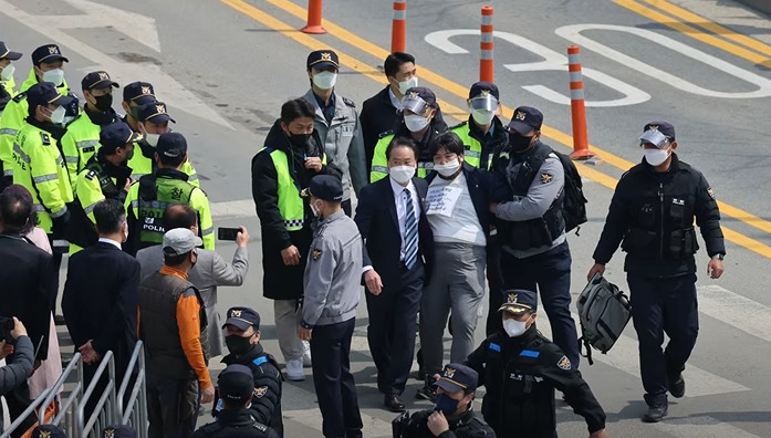 박근혜 전 대통령에게 소주병을 투척한 사람이 경찰에게 연행되고 있다.[가로세로연구소 영상 캡처]