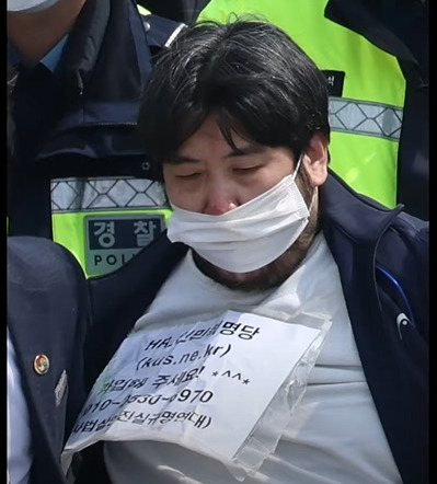 소주병으로 추정되는 물건을 던진 범인의 가슴에 가입단체와 연락처 등이 적힌 종이가 부착되어 있다.[가로세로연구소 영상 캡처]