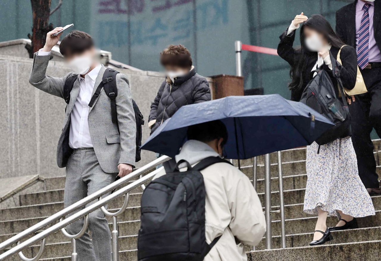 서울역 인근에서 비를 맞으며 길을 걷고 있는 시민들. [연합]