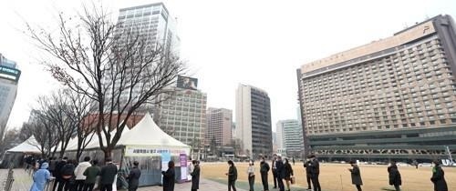 People wait in line to receive tests at a COVID-19 testing station in Seoul on March 11, 2022. (Yonhap)