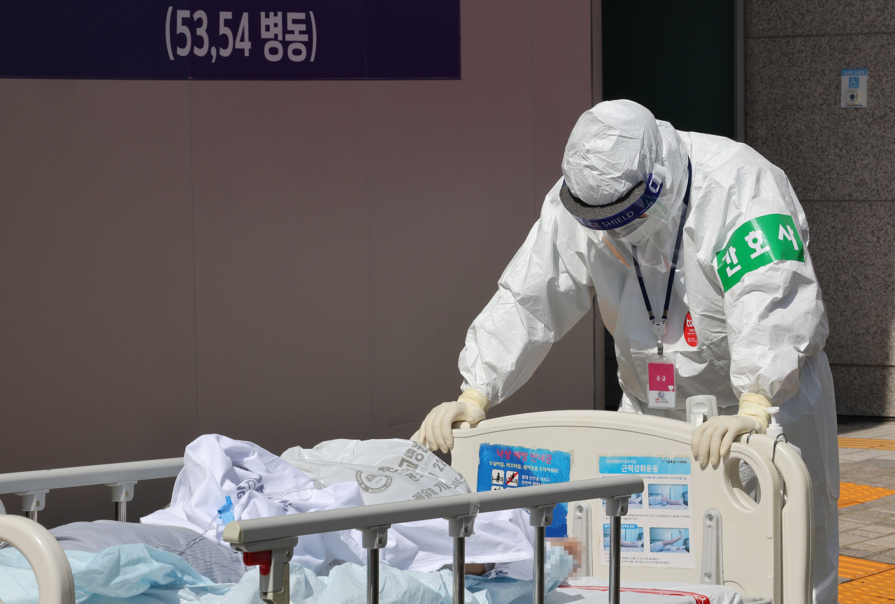 지난 29일 서울 은평구 서북병원에서 한 의료진이 코로나19 환자를 옮기고 있다. [연합]