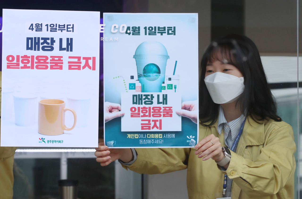 코로나19 발생 후 한시적으로 허용됐던 카페 등 식품접객업 매장 내 일회용품 사용이 이달 1일부터 다시 금지돼, 30일 오전 광주 북구의 한 카페에서 북구청 자원순환팀 직원들이 안내 홍보문을 붙이고 있다. [연합]