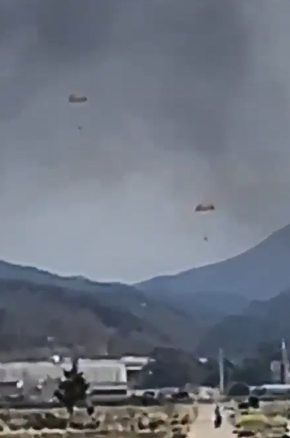 Pilots parachute down in the sky over a field in Sacheon, South Gyeongsang Province, southeastern South Korea, on Friday, after two Air Force KT-1 trainer jets collided in midair and crashed. (Yonhap)