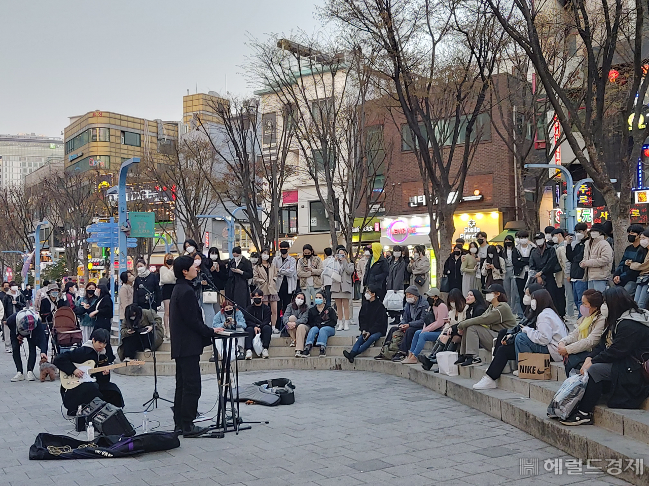 사회적 거리두기 단계적 완화가 진행 중이던 이달 3일 오후 서울 마포구 홍대거리의 시민들이 마스크를 낀 채 버스킹 공연을 관람하고 있다. 거리두기 완화 분위기가 이달부터 대학가에도 확산되고 있다. 김희량 기자