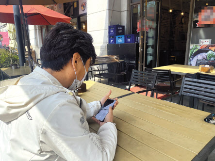 지난 4일 오후 2시께 서울 영등포구 여의도에서 17년째 순대국밥집을 운영하는 자영업자 이모(56) 씨가 휴대폰을 들여다보고 있다. 신주희 기자