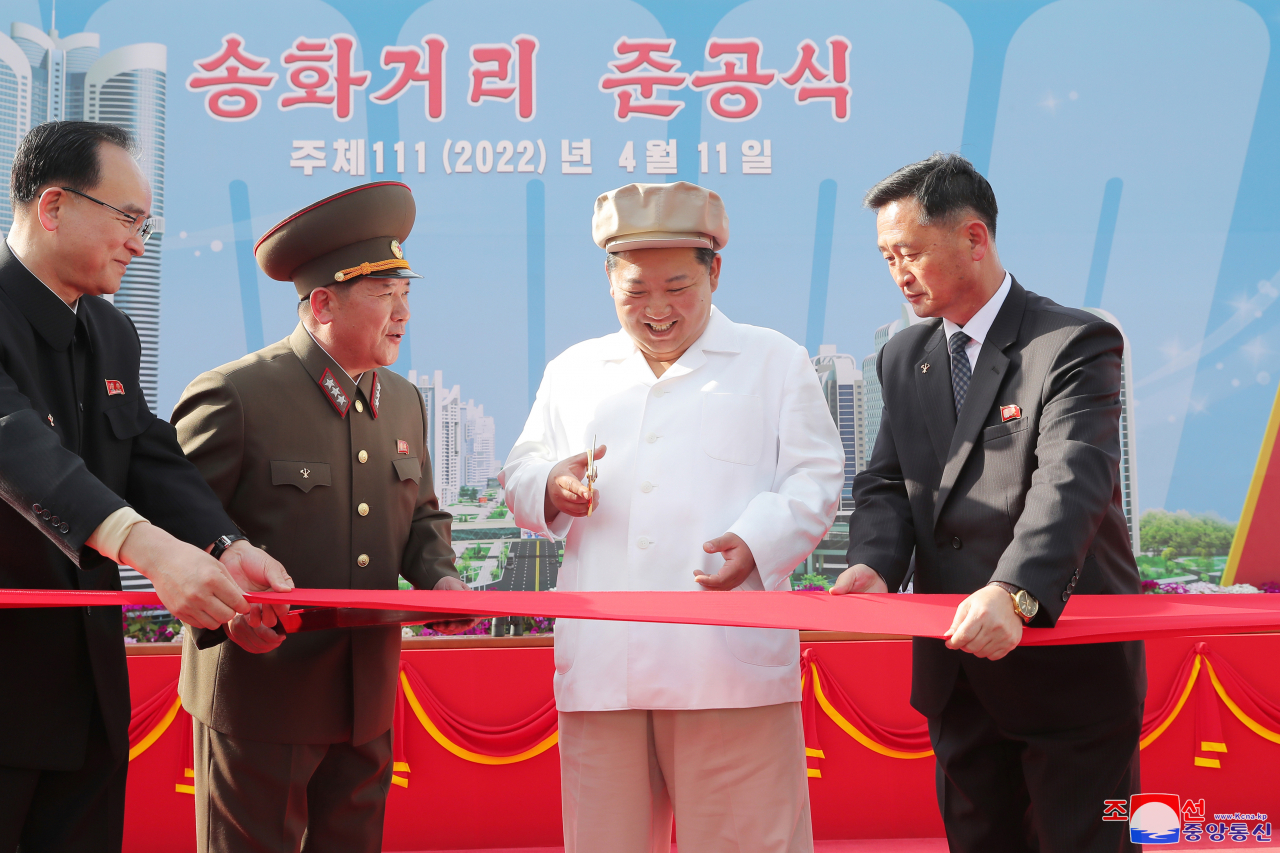 This photo, released by the Korean Central News Agency, shows North Korean leader Kim Jong-un (2nd from R) cutting the red tape during a dedication ceremony on Monday, for the Songhwa District, built in eastern Pyongyang to resolve the capital city's housing shortage. (KCNA)