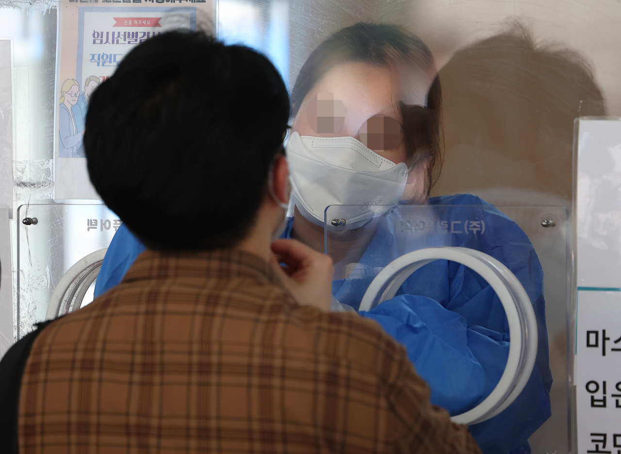 코로나19 선별진료소와 임시선별검사소 신속항원검사 중단 이틀째인 12일 오전 서울역광장에 마련된 임시선별검사소에서 의료진이 검체 채취를 하고 있다. 한편 중앙방역대책본부에 따르면 이날 신규확진자 수는 21만755명으로 집계됐다. [연합]