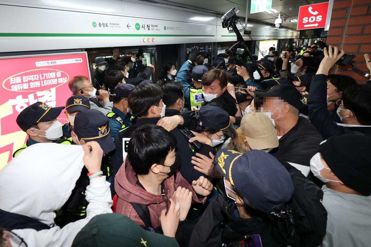 21일 오전 서울 지하철 2호선 시청역에서 경찰이 전국장애인차별철폐연대(전장연)의 출근길 지하철 탑승 시위로 열차 출발이 오래 지연되자 전장연 회원들을 열차에서 끌어내려고 시도하고 있다. 이날 재개된 전장연의 지하철 탑승 시위는 장애인 권리 예산 등에 대한 대통령직 인수위의 답변을 기다리겠다며 시위를 중단한 지 22일 만이다. [연합]