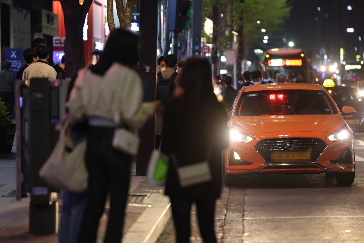 신종 코로나바이러스 감염증(코로나19) 방역을 위한 사회적 거리두기가 해제된 이래, 자정을 막 넘긴 시간에 서울 강남역 인근에서 시민들이 택시를 잡기 위해 서 있다. 같은 날 오랜만에 늦은 시간까지 외부 활동을 즐기는 사람들이 늘면서 ‘택시 대란’이 벌어졌다. [연합]