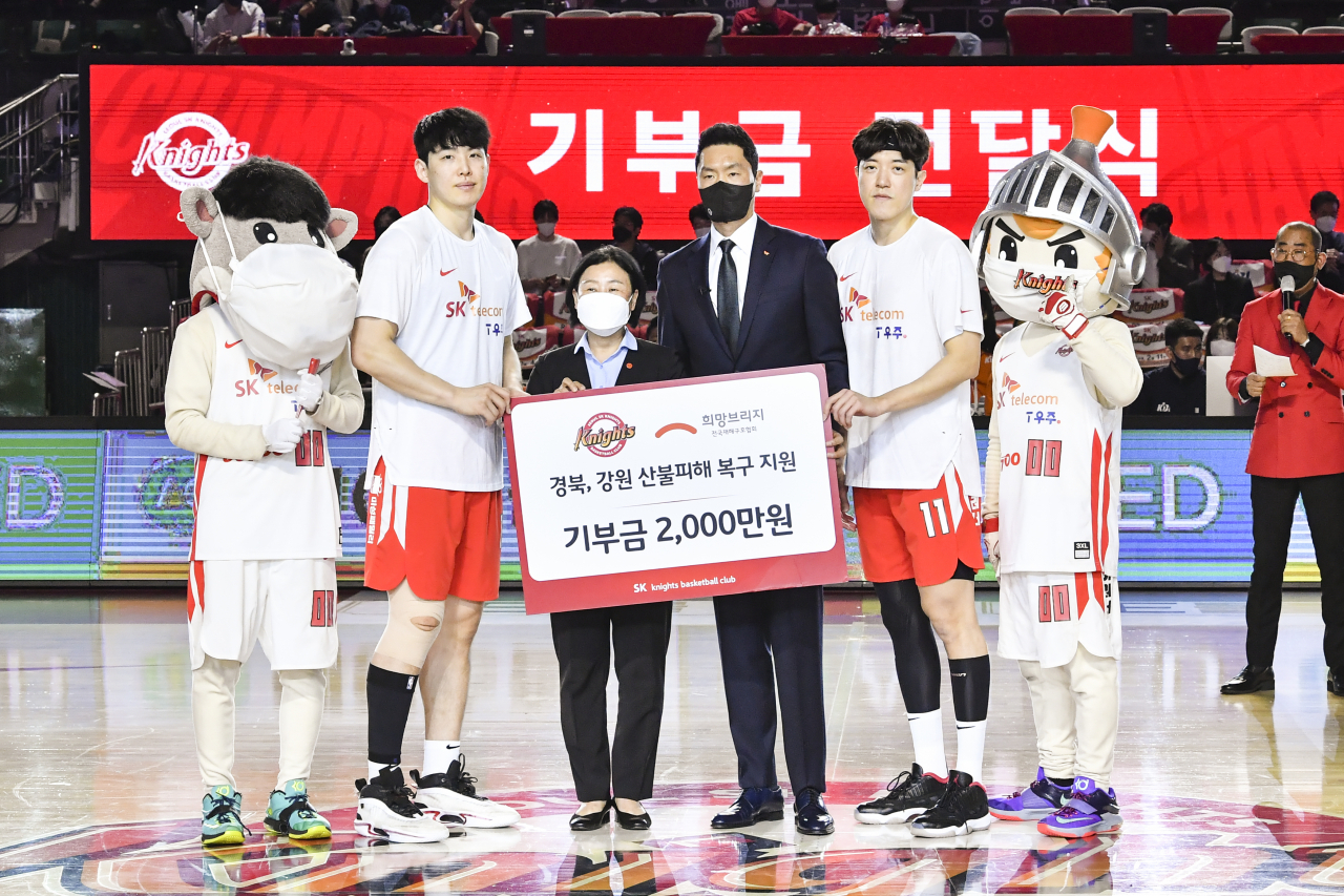 4강 PO 첫 경기 시작 전 SK나이츠의 전희철 감독(왼쪽서 4번째), 최부경(왼쪽서 2번째), 허일영(왼쪽서 5번째)가 김정희 희망브리지 사무총장(왼쪽서 3번째)에게 기부금을 전달하는 모습. [SK텔레콤 제공]