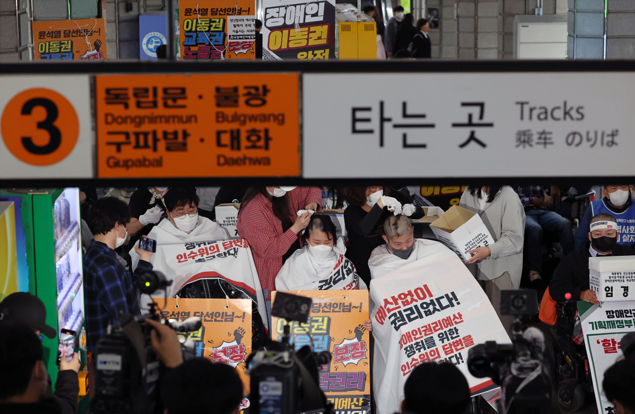 21일 오전 서울 종로구 지하철 3호선 경복궁역 승강장에서 전국장애인차별철폐연대(전장연)가 지하철 탑승 시위를 마친 후 삭발식을 하고 있다. [연합]