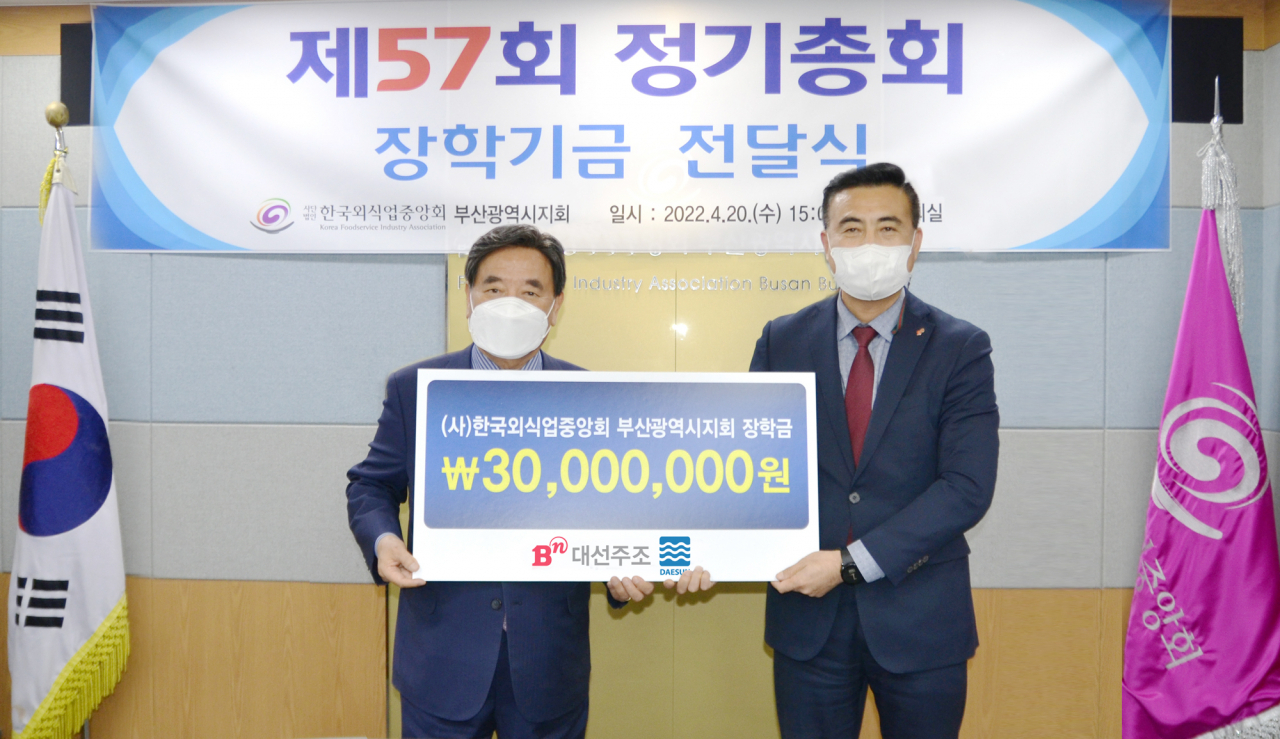 20일 ‘제57회 한국외식업중앙회 부산시지회 정기총회’에서 대선주조 김상준 지점장(오른쪽)이 한국외식업중앙회 강인중 부산광역시지회장(왼쪽)에게 소속회원 자녀들을 위한 장학금 3000만원을 전달했다. [대선주조 제공]