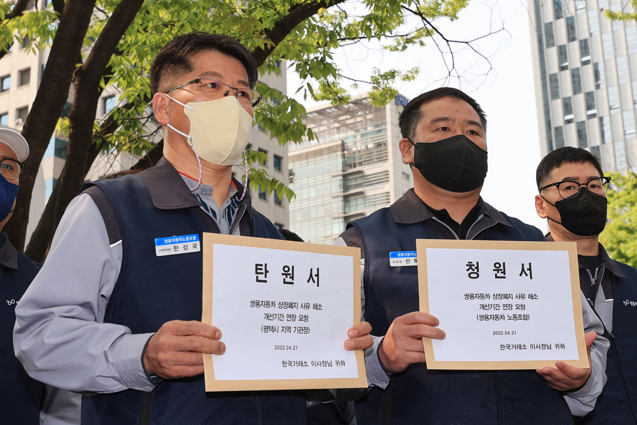 [사진=21일 오전 서울 영등포구 여의도 한국증권거래소 앞에서 열린 쌍용차 상장폐지 사유 해소를 위한 개선 기간 연장 요구 기자회견에서 한상국 쌍용차노조 수석부위원장(왼쪽부터)과 선목래 쌍용차 노조위원장이 탄원서와 청원서를 들고 있다.][연합]