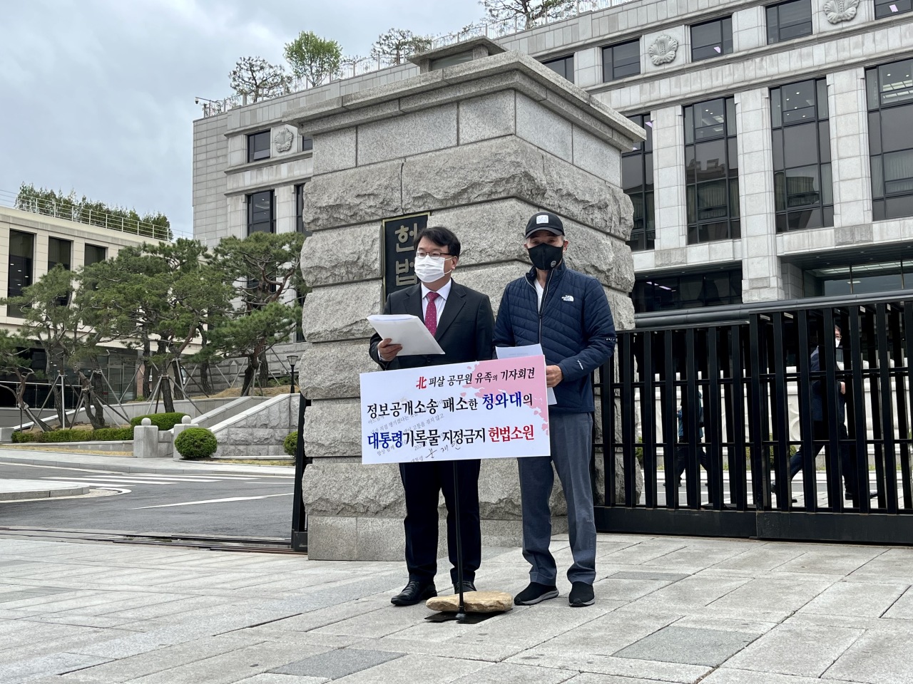 Lee Rae-jin (right), brother of an official killed by North Korea’s military while drifting in the sea, and Kim Ki-yun, a lawyer representing the family, speak to reporters outside the Constitutional Court in central Seoul on April 13. (Kim Arin/The Korea Herald)