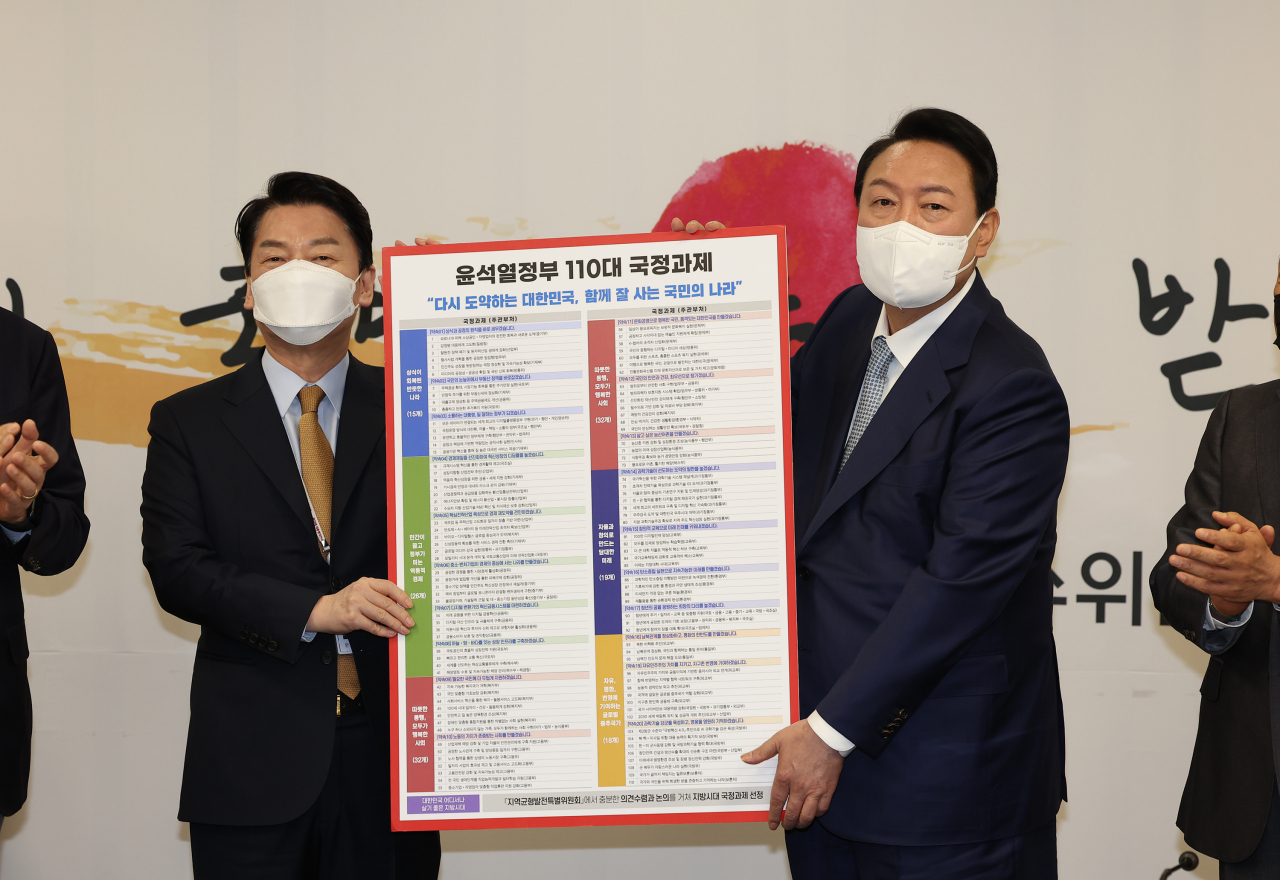 윤석열 20대 대통령 당선인이 지난 3일 서울 종로구 삼청동 대통령직인수위원회에서 열린 전체 회의에서 안철수 인수위원장으로부터 인수위가 준비한 110대 국정과제를 전달받고 있는 모습. [인수위사진기자단]