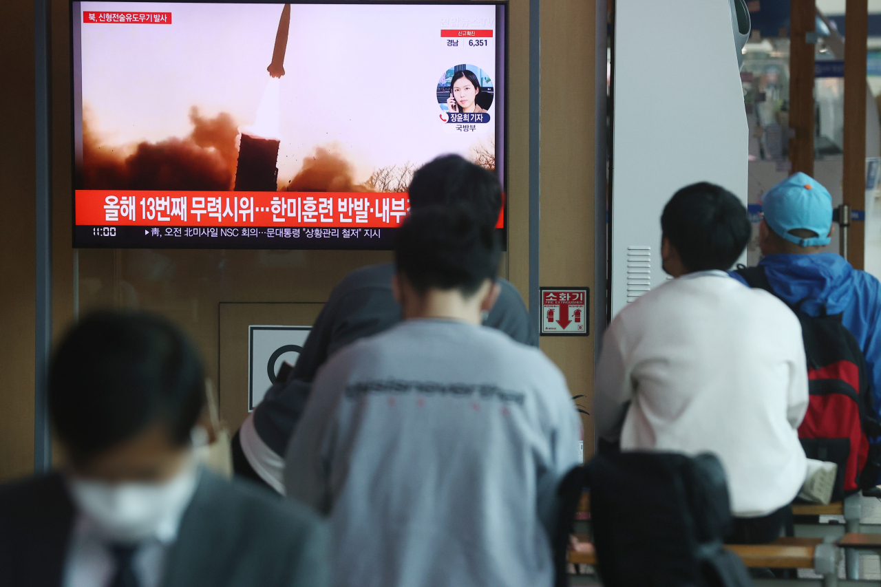 Passersby watch a TV report of North Korea’s missile launch at Seoul Station. (Yonhap)