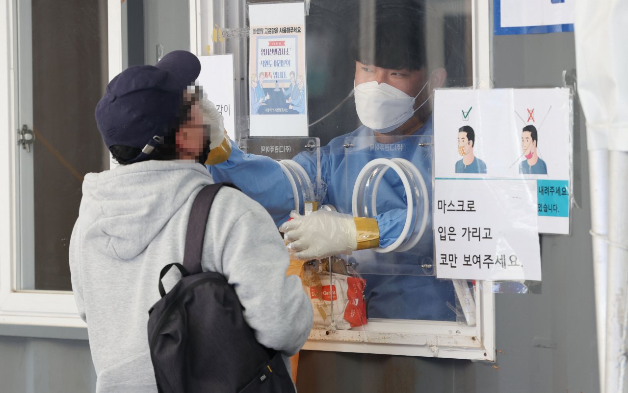 A health worker conducts a COVID-19 test on a citizen at a testing site in front of Seoul Station on Thursday. (Yonhap)