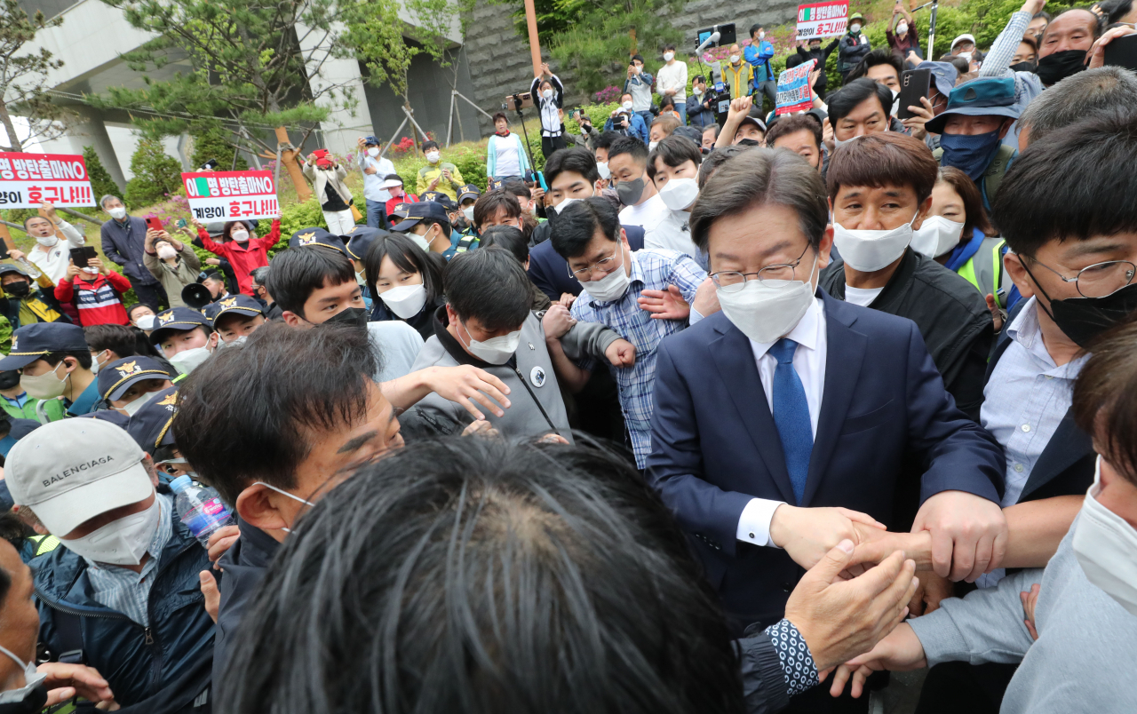 8일 인천 계양산 야외공연장에서 열린 이재명 더불어민주당 상임고문 계양을 보궐선거 출마 선언 기자회견에서 이 후보 뒤로 출마 반대 구호 피켓을 든 국민의힘 지지자들의 모습이 보인다. [연합]