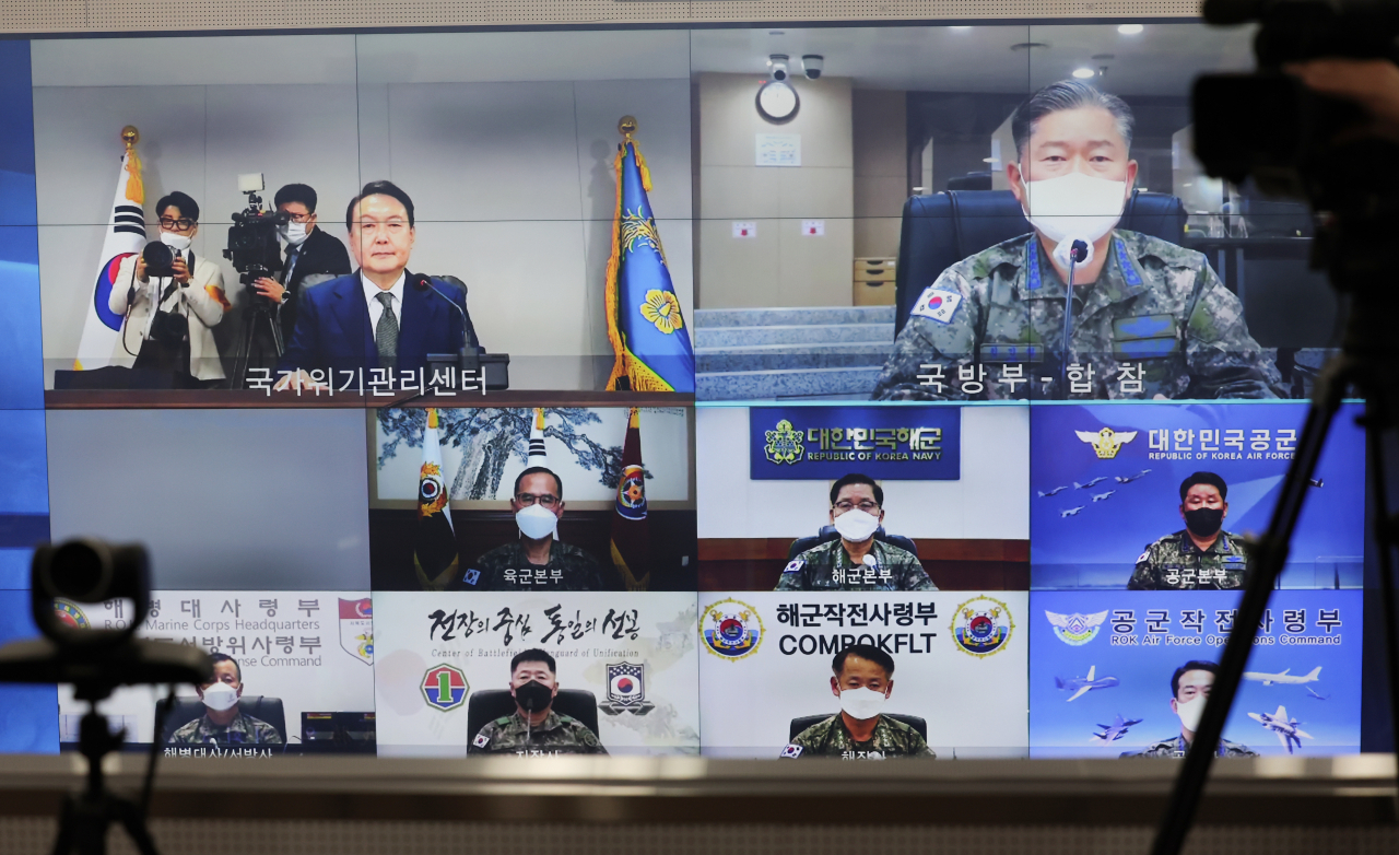 윤석열 대통령이 10일 0시 서울 용산 대통령실 국가위기관리센터 상황실에서 국군통수권을 이양 받은 뒤 원인철 합동참보본부 의장으로부터 북한 군사동향과 우리군 대비태세에 보고를 받으며 집무를 시작하고 있다. 연합뉴스