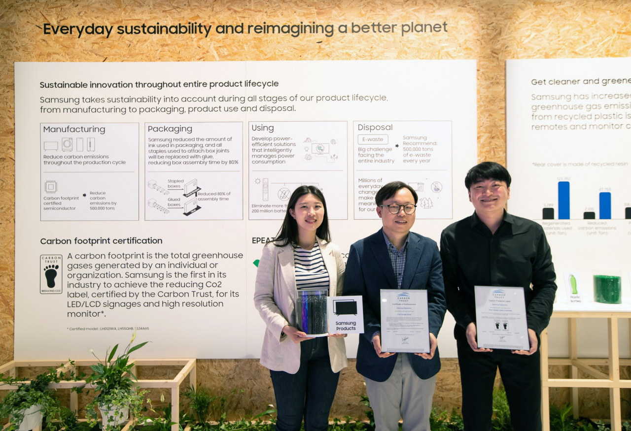 ISE 2022가 열리고 있는 스페인 바르셀로나 피라 그라 비아 전시장에서 이종포 삼성전자 영상디스플레이사업부 엔터프라이즈 개발 상무(가운데)와 개발자들이 사이니지 제품 탄소 발자국 인증서와 제품에 활용되는 재생 플라스틱을 들고 있다. [삼성전자 제공]
