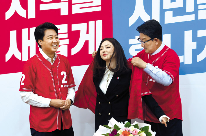 당구선수 차유람이 13일 오전 국회에서 열린 국민의힘 입당 환영식에 참석해 이준석 대표가 바라보는 가운데 권성동 원내대표가 입혀주는 당 지방선거 유니폼을 착장하고 있다. [연합]