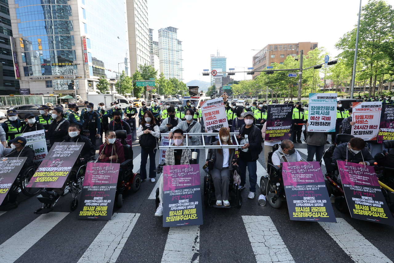 전국장애인차별철폐연대(전장연) 회원들이 16일 오전 서울 신용산역에서 대통령실로 향하는 한강대로의 횡단보도를 점거한 채 장애인 권리 예산 보장 등을 요구하는 시위를 하고 있다. 이날 시위 참가자들은 3~5개 차선의 차량 통행을 막아 출근길 교통 혼잡이 빚어졌다. [연합]