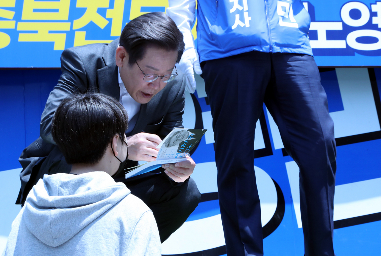 인천 계양을 국회의원 후보인 더불어민주당 이재명 총괄선대위원장이 22일 오전 청주 성안길에서 유세 중 지지자에게 받은 저서에 사인해주고 있다. 연합뉴스